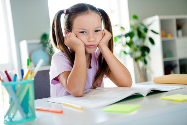 不满意的懒学生坐在椅子上的照片，手摸脸颊，打开了书，桌面房子里面图片下载