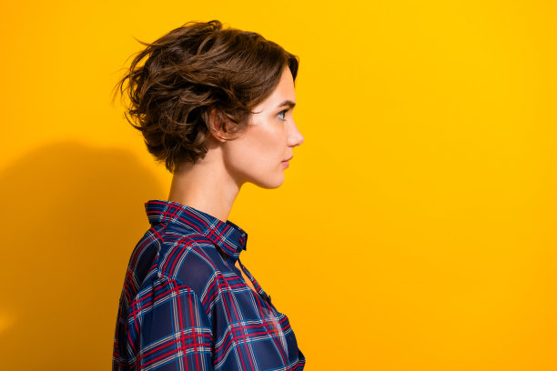 侧面侧面照片自信的女人与鲍勃发型穿着格子衬衫看标志空白空间孤立的黄色背景图片下载