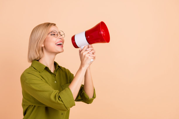 可爱的积极的女人与鲍勃头发的照片，穿着绿色衬衫，在米色背景上对着扬声器尖叫图片下载