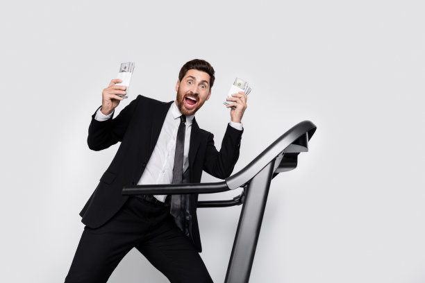 惊讶的企业人士的肖像头奖得主持有美元钞票跑步机空空间孤立的灰色背景图片下载