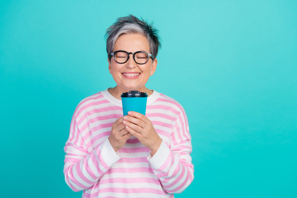 照片的梦幻甜美的女人穿着粉红色的套衫享受凉茶的香气空空间孤立的蓝绿色背景图片下载