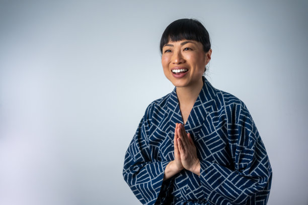 快乐的日本妇女穿着传统和服，背景是灰色的图片下载