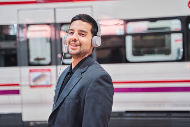 一个年轻的拉丁男子戴着耳机看着镜头听着音乐，背景是一个地下乐队。图片下载