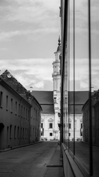 黑白照片，教堂的塔楼反射在建筑物的窗户上。图片下载
