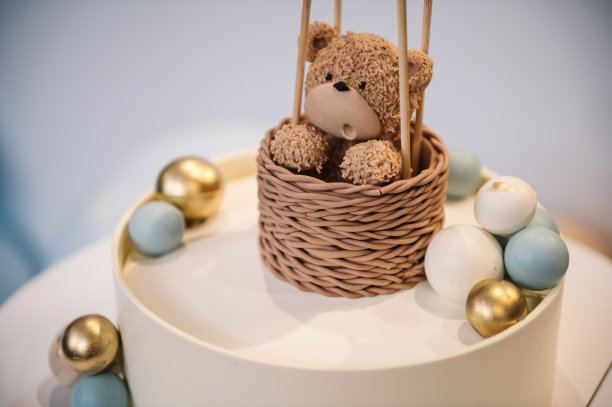 时髦的蛋糕上有男孩或女孩的玩偶熊。生日聚会用的装饰有蓝色、金色、棕色气球的蛋糕。庆祝洗礼的概念。美味的接待。照片墙，拱门装饰。特写镜头。图片下载