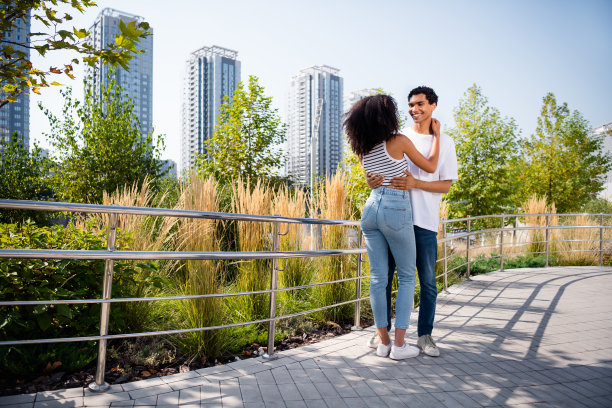 照片正面可爱的妻子丈夫穿着休闲服拥抱散步河堤外的城市街道图片下载