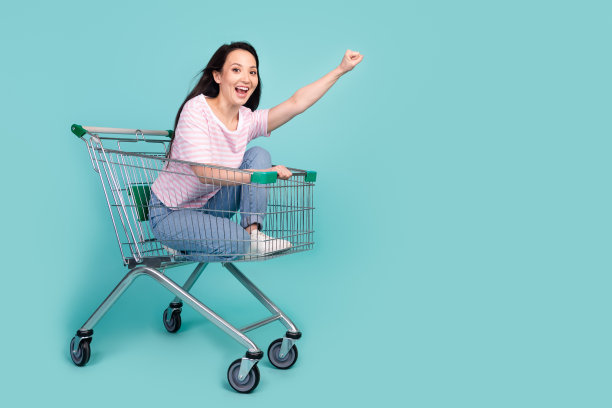 全身照片兴奋时髦的混合种族女士穿着条纹t恤骑快速超市手推车空空间孤立蓝绿色背景图片下载