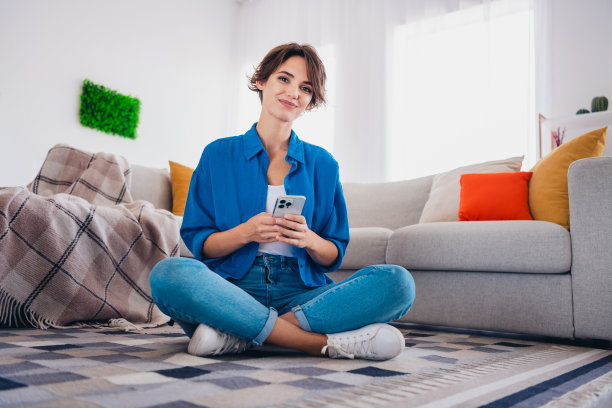 迷人可爱的漂亮女孩坐在现代公寓的地毯上独自在室内度过周末的照片图片下载