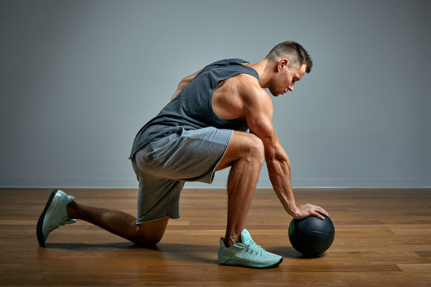 强壮的男人用健身球做运动。灰色背景上完美体格的男子照片。力量和动力。图片下载