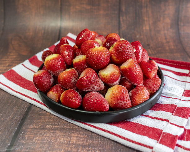 冷冻草莓放在木制背景的黑色盘子里。用于社交网络的Square照片。俯冲的照片。图片下载