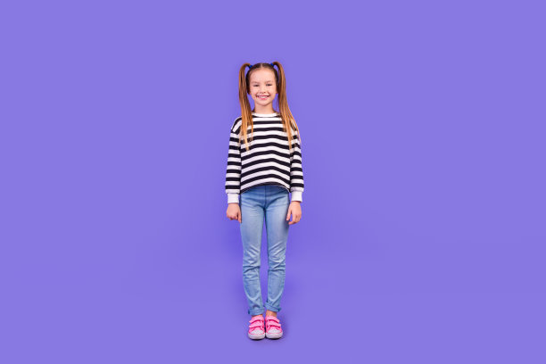 时髦欢快的小孩穿条纹毛衣走路微笑空空间孤立的紫罗兰色背景的全长照片图片下载