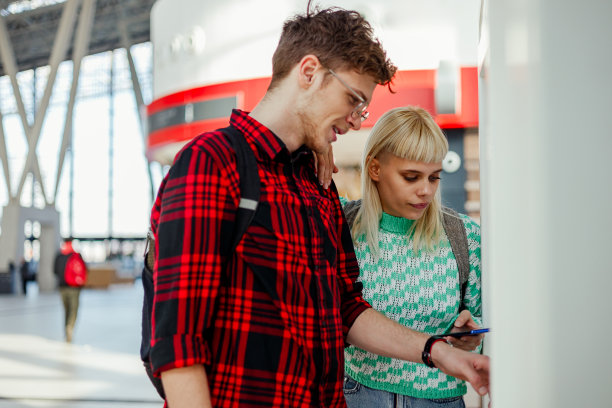 一对夫妇站在火车站售票机旁买票。图片下载