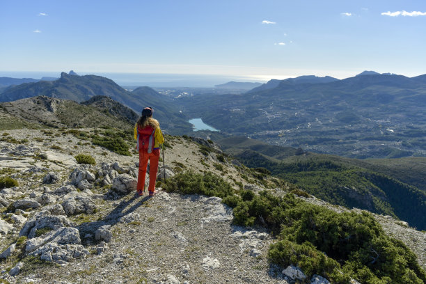 一个中年成年妇女俯瞰瓜达莱斯特湖从高岩石，科斯塔布兰卡，阿利坎特，西班牙-股票照片图片下载