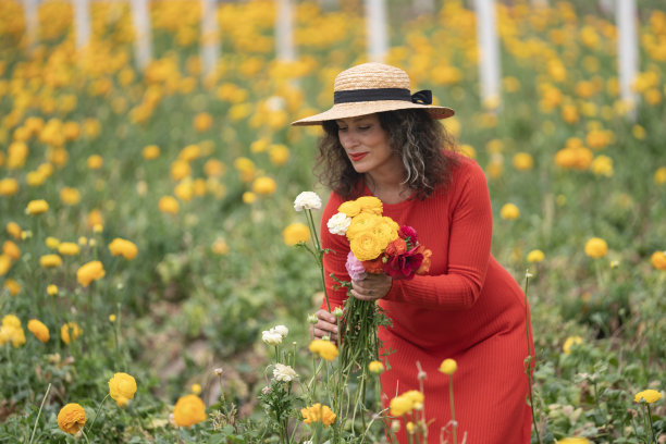 穿红色连衣裙在花园里摘花的女人照片图片下载