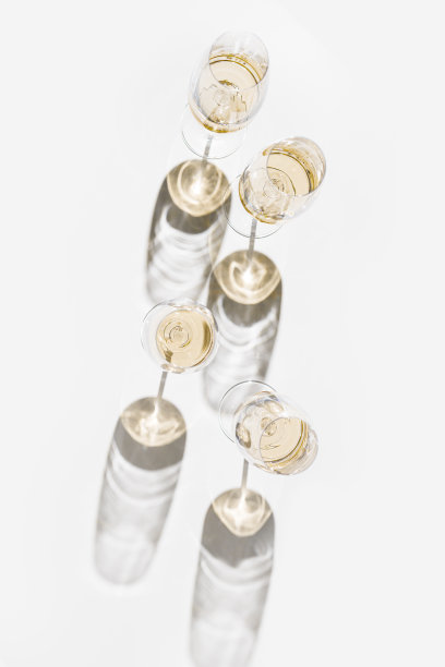 全白酒杯最小的风格以上视图。假日美学静物照片，俯视图闪闪发光的水晶酒杯在自然的阳光下，硬阴影，简单的酒精饮料背景，copyspace图片下载