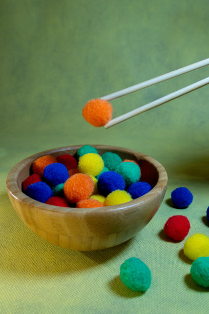 人学习如何使用筷子吃饭和练习用木碗与彩色球垂直图片图片下载