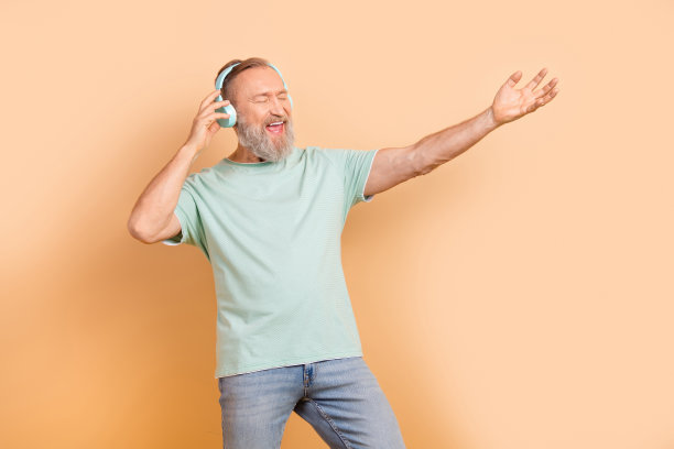 照片的积极高兴的人穿着时髦的青色服装听声音音频播放列表孤立的米色背景图片下载