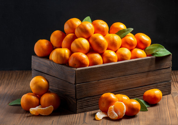 一群橙黄色的熟橘子，剥了皮，绿叶躺在那里图片下载