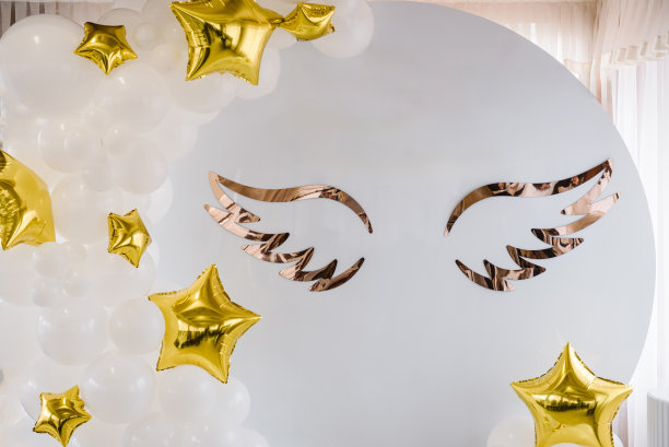 金色风格的照片区。拱门上装饰着白色、金色的气球，形状像星星，还有洗礼派对上的天使翅膀。庆祝洗礼的概念。宝宝生日派对的接待处挂在墙上。图片下载