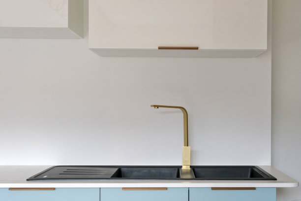 黄铜搅拌器轻敲黑色花岗岩水槽。图片下载