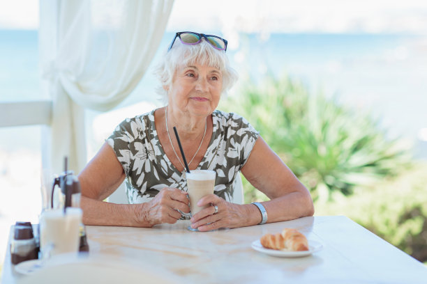 迷人的老女人坐在夏日的户外咖啡馆里图片下载