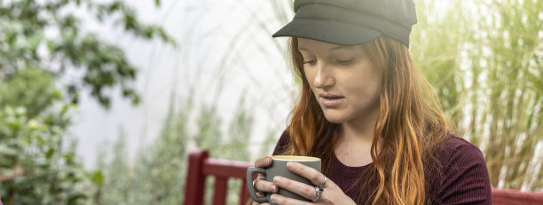 横向横幅或模板，沉思的年轻红发女子喝拿铁或咖啡在自助餐厅酒吧花园-年轻女子红发和雀斑，她的头在云-重点在脸图片下载