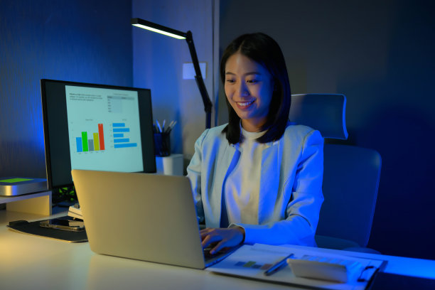 年轻勤劳的女商人晚上在办公室加班的照片。图片下载