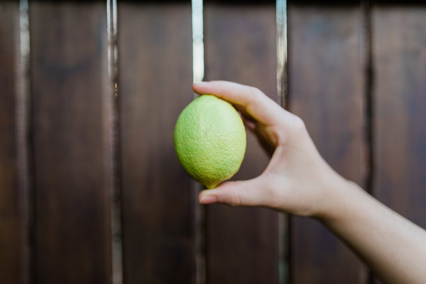 人手中的柠檬在木制背景上图片下载