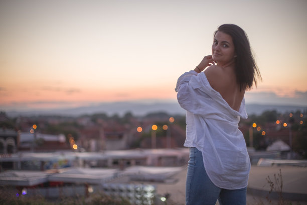 城市上空夕阳下自信快乐的年轻女子的肖像图片下载