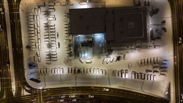 无人机拍摄的建筑物附近的停车场和积雪覆盖的汽车在冬天的早晨图片下载