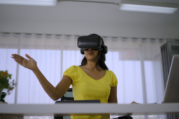 年轻女子使用虚拟现实眼镜进行演示。图片下载