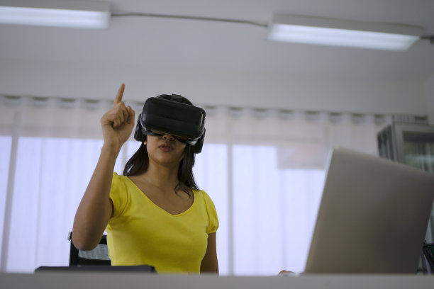 年轻女子使用虚拟现实眼镜进行演示。图片下载
