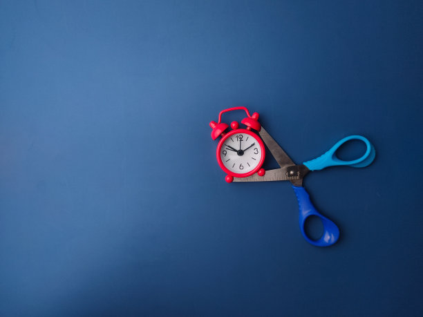 顶视图蓝色剪刀与红色闹钟在蓝色背景图片下载