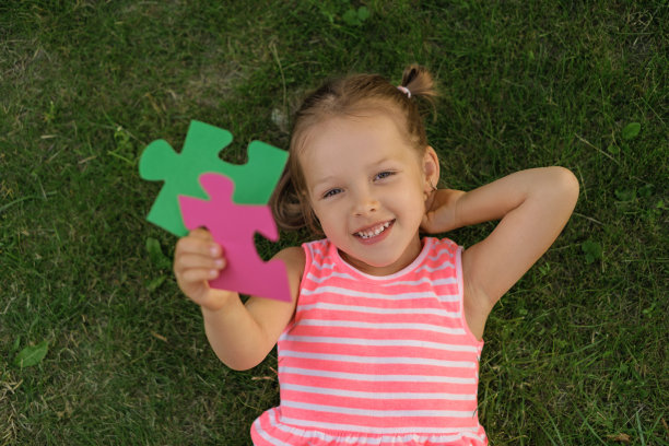 这个孩子手里拿着两块大拼图。照片上的主题是逻辑思维和发展图片下载