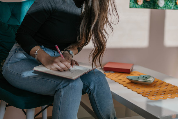 一个女人在笔记本上写字的特写照片图片下载