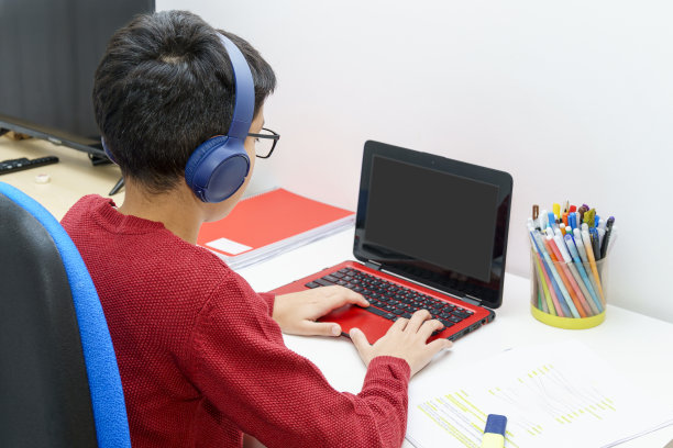 年轻的学生用笔记本电脑做作业，戴着无线耳机在专门的学习空间参加在线课程图片下载