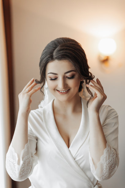 深色头发的新娘抚摸着自己的脸。漂亮的妆容和发型。大量的面纱。婚礼的照片。美丽的新娘图片下载