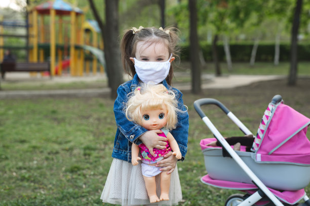 小女孩抱着戴口罩的娃娃，以抵御冠状病毒和空气污染pm2.5。图片下载