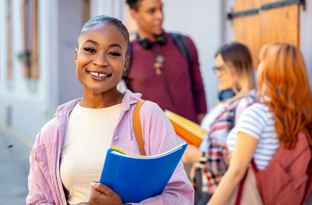 一个微笑的非裔美国女学生和朋友对着镜头的照片。图片下载