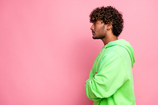 侧面资料照片自信英俊的阿拉伯人没有刮胡子的家伙在连帽衫交叉的手看空空间孤立在粉红色的背景图片下载