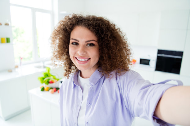 照片的甜美积极的女人穿紫色衬衫做饭在公寓厨房里录制视频vlog图片下载