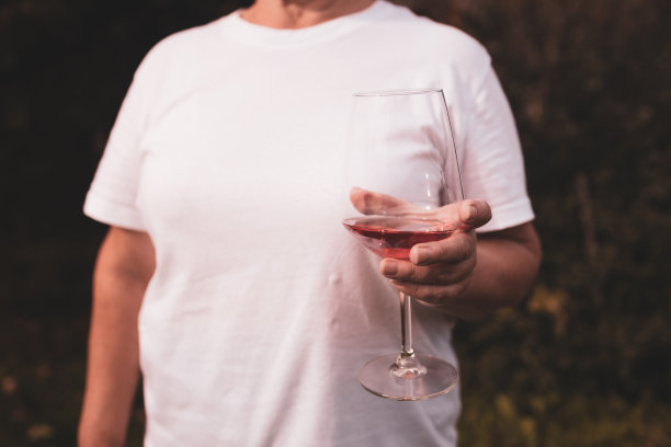 手捧一杯粉红色的葡萄酒，在后院模糊的背景下，在户外玩耍。图片下载
