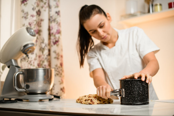 穿白衣的女孩从烤盘里拿出馅饼图片下载