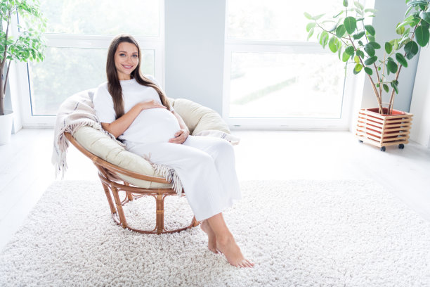 照片开朗可爱可爱可爱的怀孕女孩坐在舒适的椅子上白色的光在平漂亮的内部图片下载