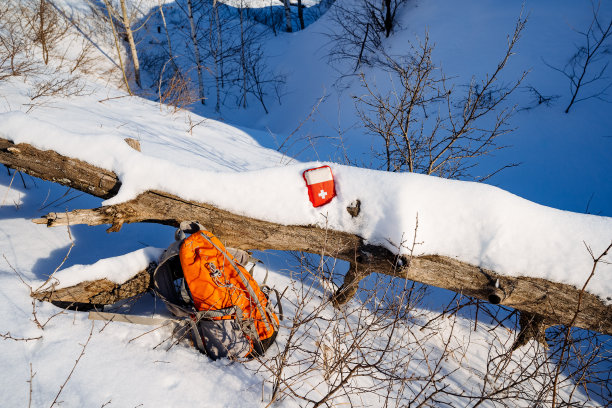 冬季森林雪地上躺着的背包和急救箱，阳光明媚的天气，露营者的装备，荒野求生的装备。图片下载