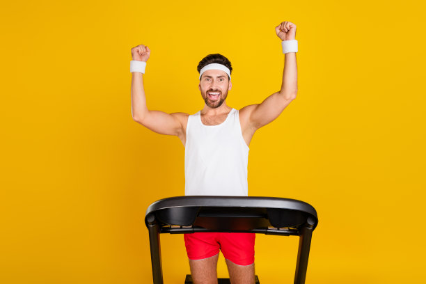 滑稽的幸运儿运动服举起拳头赢得跑步机比赛的照片孤立的黄色背景图片下载