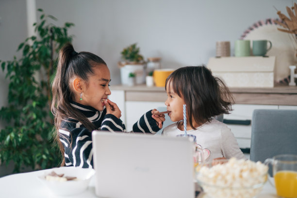 两个可爱的姐妹在家里的餐桌上吃巧克力的照片图片下载