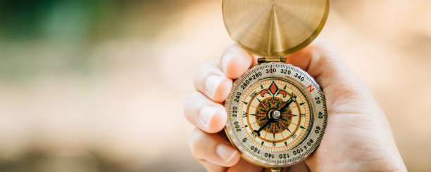 在茂密的森林里，一只手拿着指南针，传达着指引和探索的主题。这张图片与旅行生活方式和有效的商业计划和成功有关。图片下载