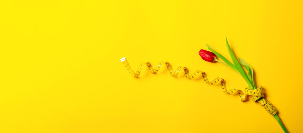 一个红色的郁金香和厘米胶带在黄色的背景与复制空间文本的地方。健身贺卡。国际妇女节或母亲节。缝纫工艺品爱好店。花店。减肥图片下载