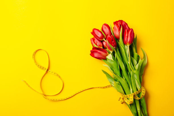 郁郁葱葱的红色郁金香花束和8号形状的厘米胶带在黄色背景上与复制空间。健身贺卡。国际妇女节或母亲节。缝纫的爱好。花店图片下载